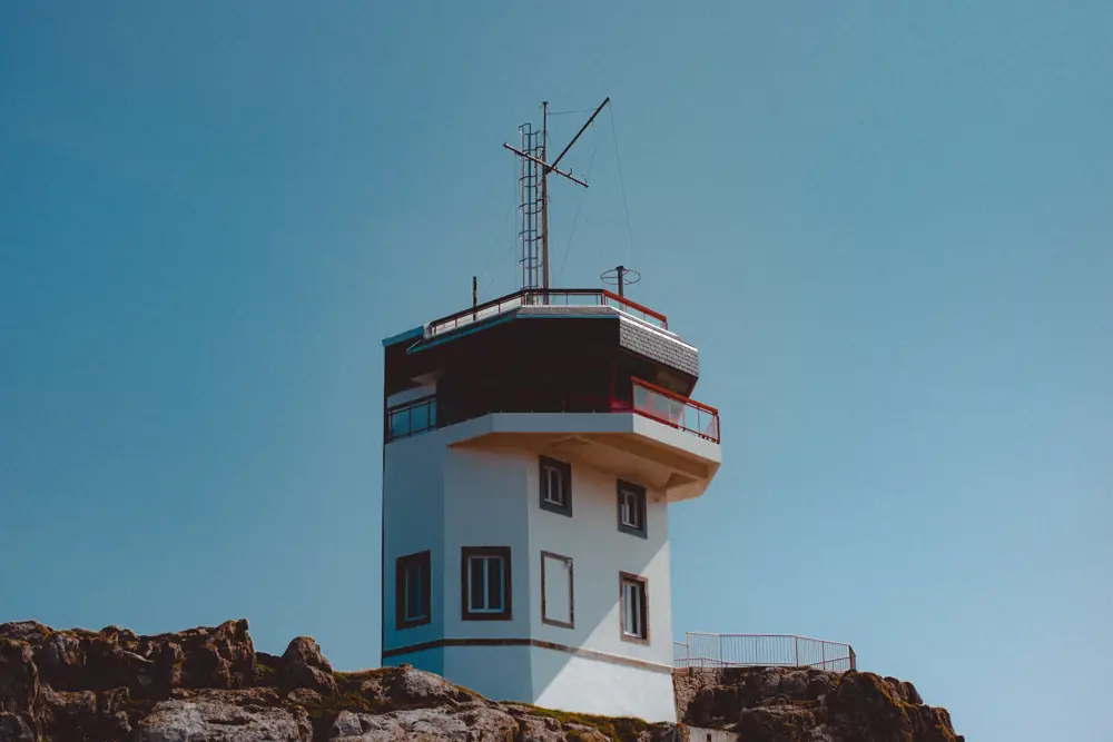 Sémaphore côtier posé sur son promontoire rocheux, sous un ciel bleu.