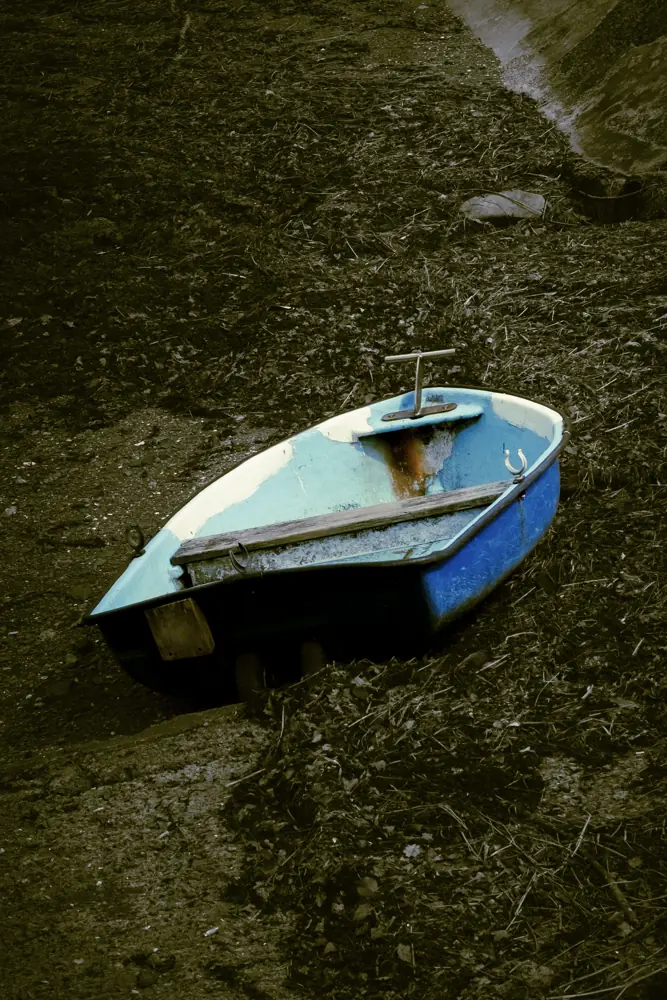 Un petit doris bleu posé à terre, vu de dessus.
